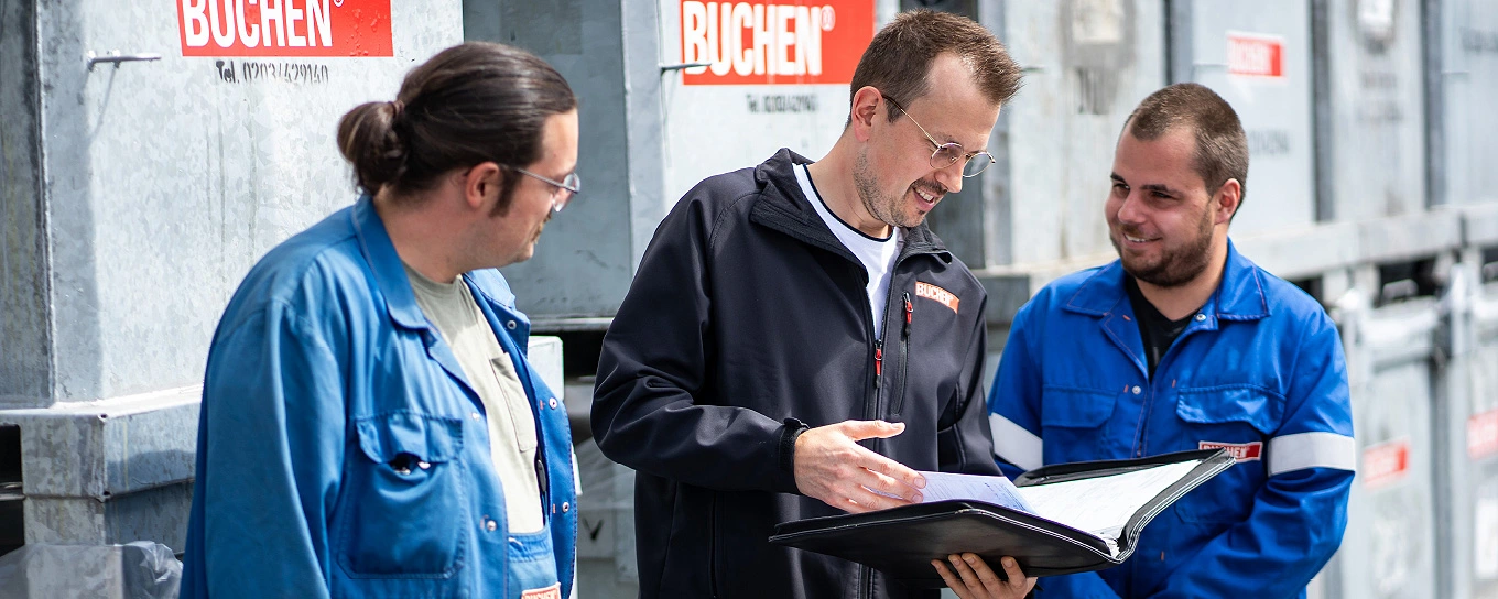 Ein Mitarbeiter ohne Schutzkleidung gibt zwei BUCHEN Mitarbeitern eine Sicherheitsunterweisungen