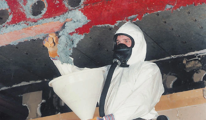 Mitarbeiter in persönlicher Schutzausrüstung führt Asbestsanierung durch